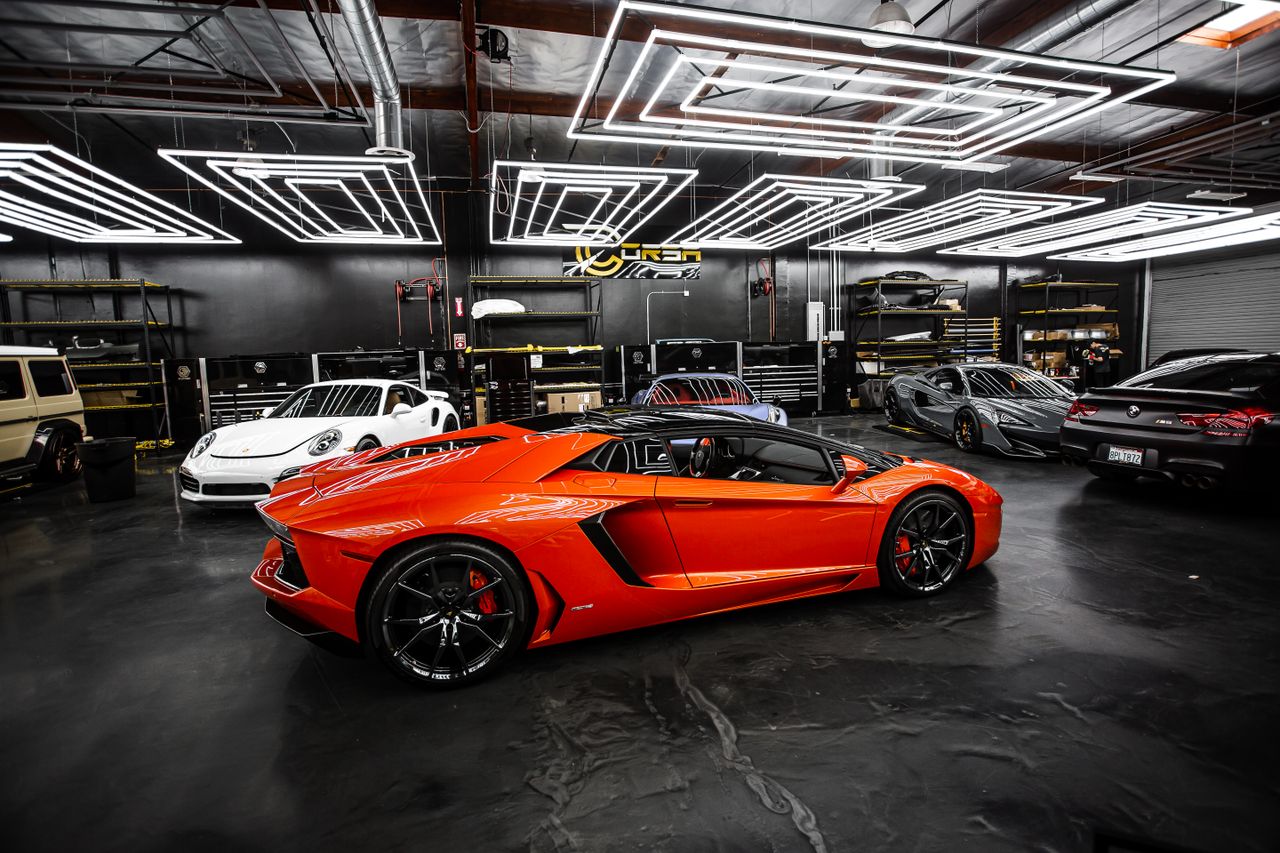 services-01 High-end sports cars displayed in a sleek, modern showroom with stylish lighting.